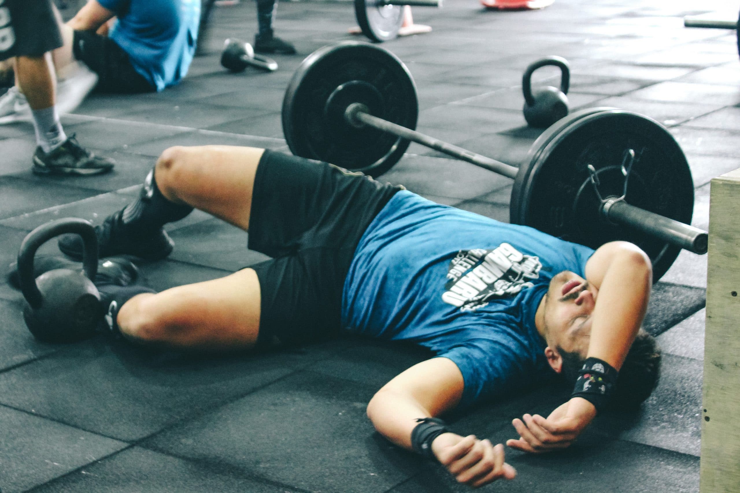 man laying on the floor looking tired after using barbell