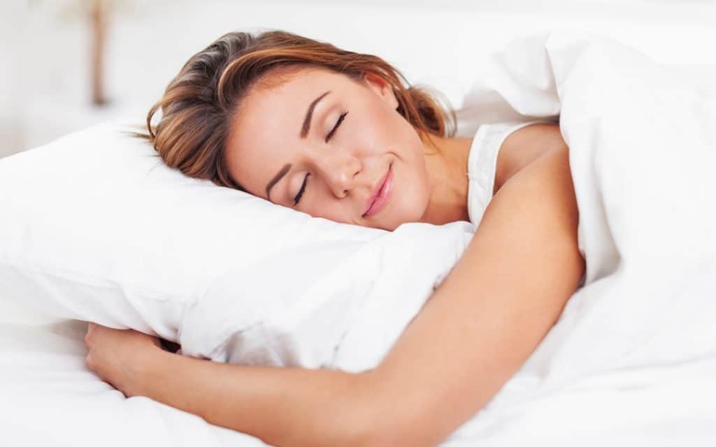 woman smiling and sleeping on bed