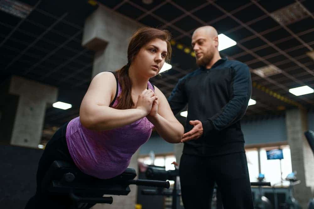 trainer helping woman at the gym