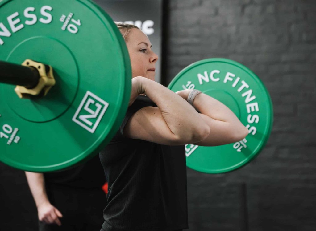female with blonde hair holding barbell